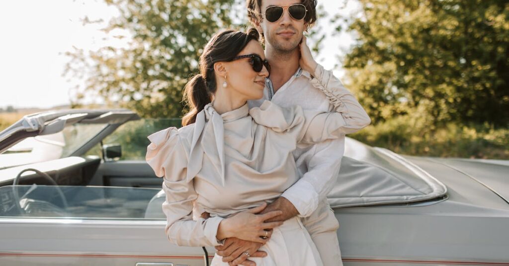 Elegant couple embracing by convertible car on a sunny day, radiating romance